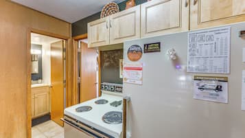 A kitchen with wooden cabinets, a white stove, and a refrigerator with various magnets and notes.