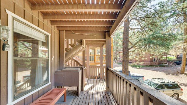 A wooden porch with a bench, a staircase, and a view of a parking area with a car. - Easy Resort Access: Angel Fire Adventure Condo! (Angel Fire)