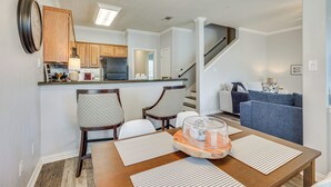 Une cuisine moderne avec des meubles en bois, un coin repas avec une table et des chaises en bois, et un salon avec un canapé et un escalier.