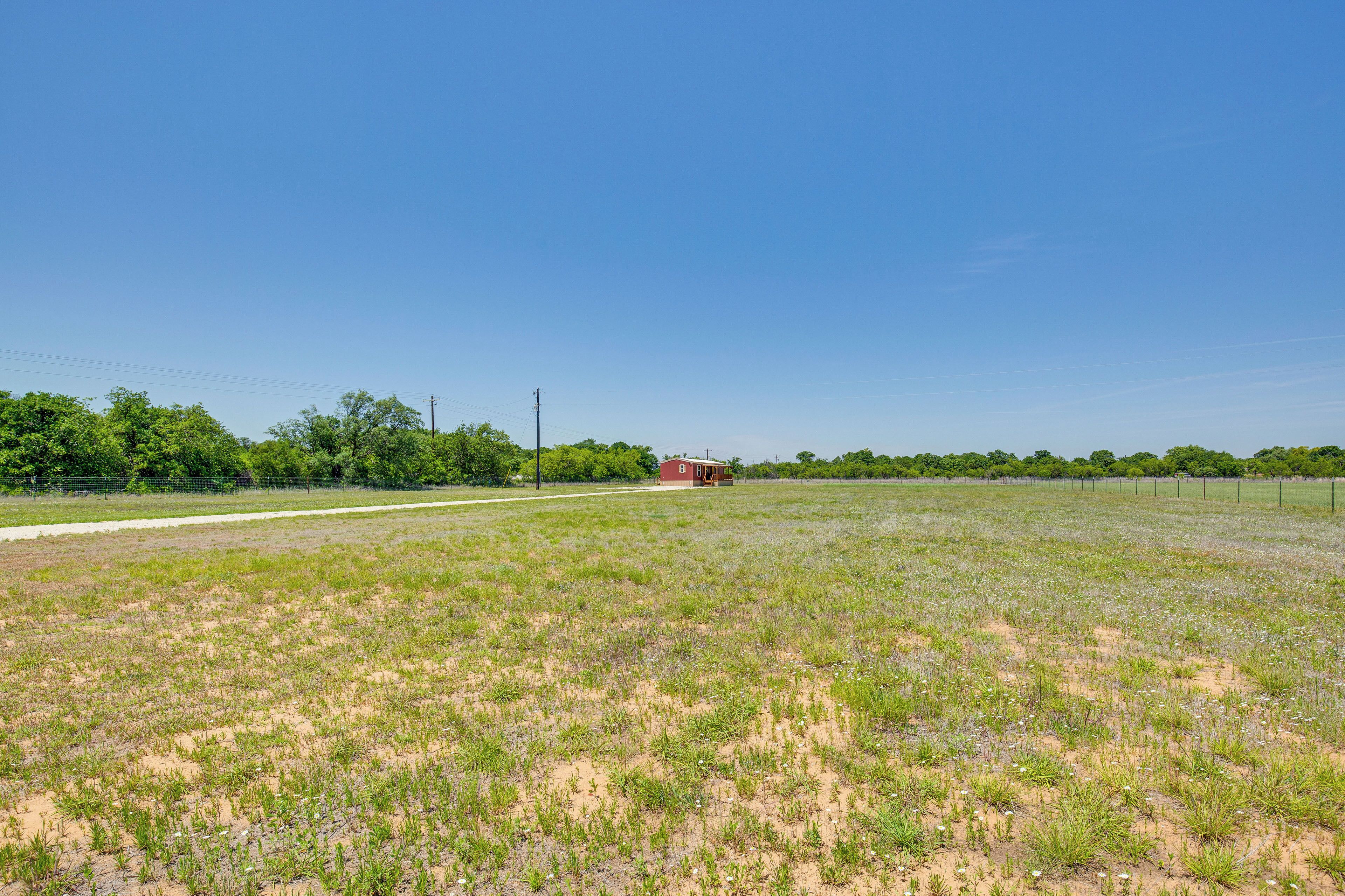 A rural landscape with a small red building in the distance, surrounded by open fields and trees.
