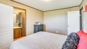 Ein Schlafzimmer mit Bett, Kommode, Spiegel und Tür.