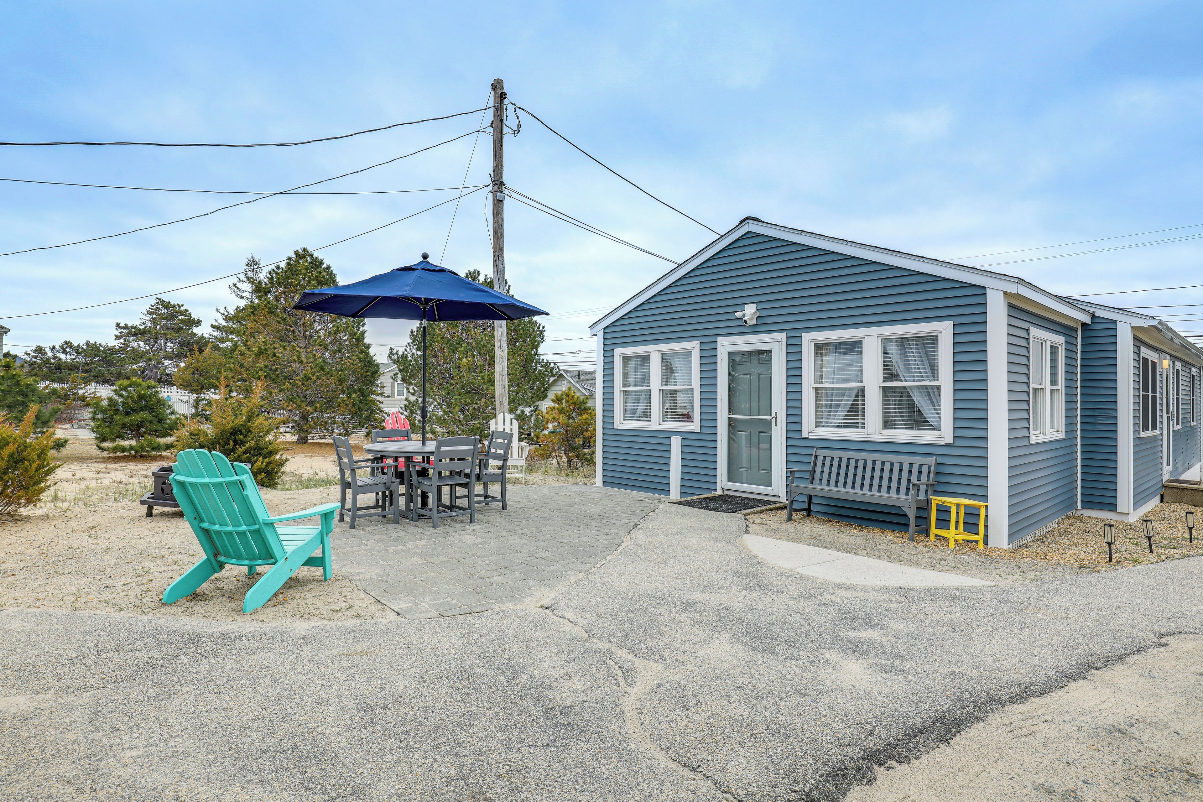 A small blue house with a porch, a table with chairs, and a blue Adirondack chair.
