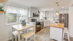 A modern kitchen with white cabinetry, stainless steel appliances, and a wooden island.