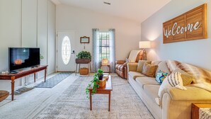 A living room with a television, sofa, and a 'Welcome' sign on the wall. - Roanoke Mountain Home: 4 Mi to Blue Ridge Parkway! (Roanoke)