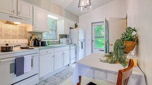 A modern kitchen with white cabinets, a stove, a microwave, and a dining table with a white tablecloth. - Roanoke Mountain Home: 4 Mi to Blue Ridge Parkway! (Roanoke)