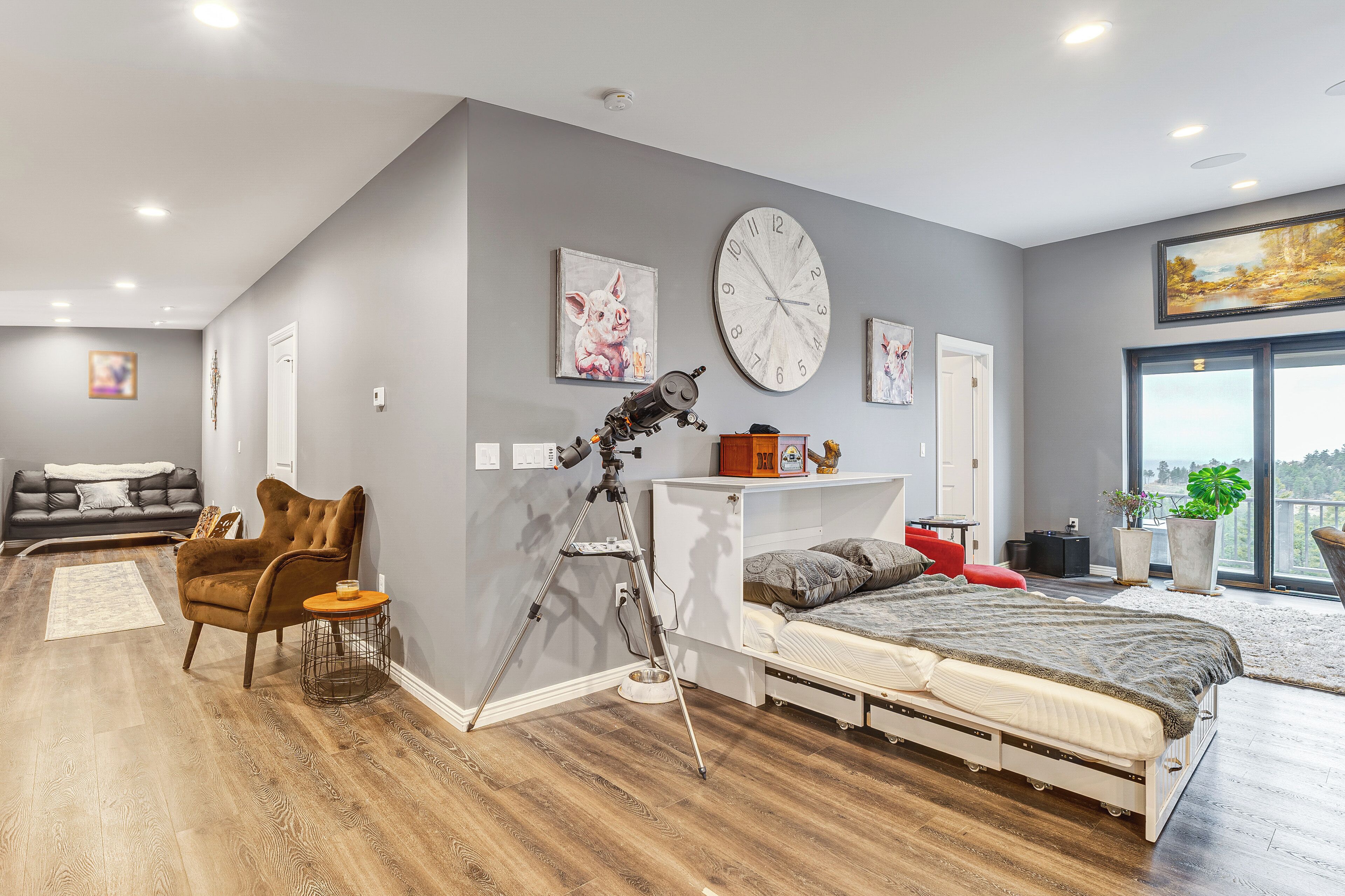 A modern bedroom with a large bed, a tripod, and a wall clock.