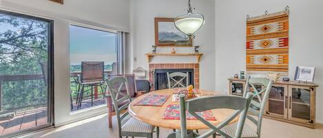 A dining area with a round table, chairs, a hanging light fixture, and a fireplace.