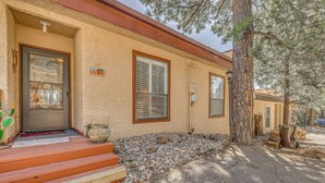 A house with a wooden porch, a stone wall, and a large tree. - Alto Townhome w/ Deck Near Ski Apache! (Alto)