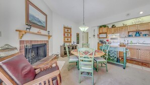 A cozy living room with a fireplace, a dining area with a round table and chairs, and a kitchen with wooden cabinets and a sink. - Alto Townhome w/ Deck Near Ski Apache! (Alto)