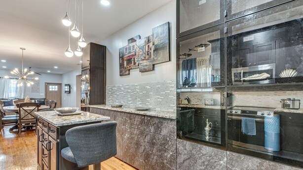 A modern kitchen with a marble countertop, a built-in oven, and a large island with bar stools. - Unbeatable Hub 1 Mi to Mercedes-benz Stadium, Dtwn (Atlanta)