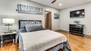 A bedroom with a bed, a nightstand, a dresser, a television, and artwork on the walls. - Unbeatable Hub 1 Mi to Mercedes-benz Stadium, Dtwn (Atlanta)