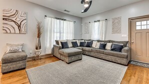 A modern living room with a sectional sofa, a small ottoman, and a decorative vase. - Unbeatable Hub 1 Mi to Mercedes-benz Stadium, Dtwn (Atlanta)