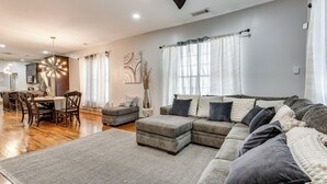 A spacious living area with a sectional sofa, ottoman, and a dining table with chairs. - Unbeatable Hub 1 Mi to Mercedes-benz Stadium, Dtwn (Atlanta)