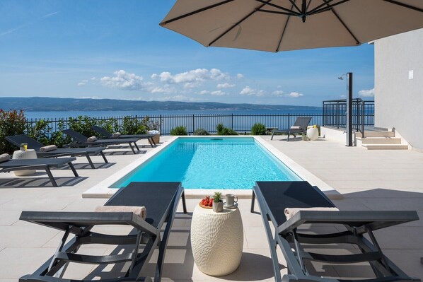 Une piscine avec des chaises longues et vue sur la mer.