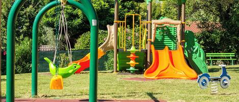 A playground with swings, slides, and a tricycle.