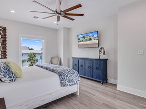 A bedroom with a bed, a ceiling fan, a window, a cabinet, and a wall-mounted picture.