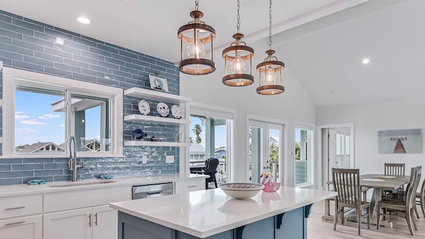 A modern kitchen with a large island, white cabinetry, and blue accents. - Flamingo House 4 Bedroom Home by RedAwning (Rockport)
