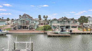 A waterfront residential area with houses featuring balconies and a dock with a boat. - Flamingo House 4 Bedroom Home by RedAwning (Rockport)