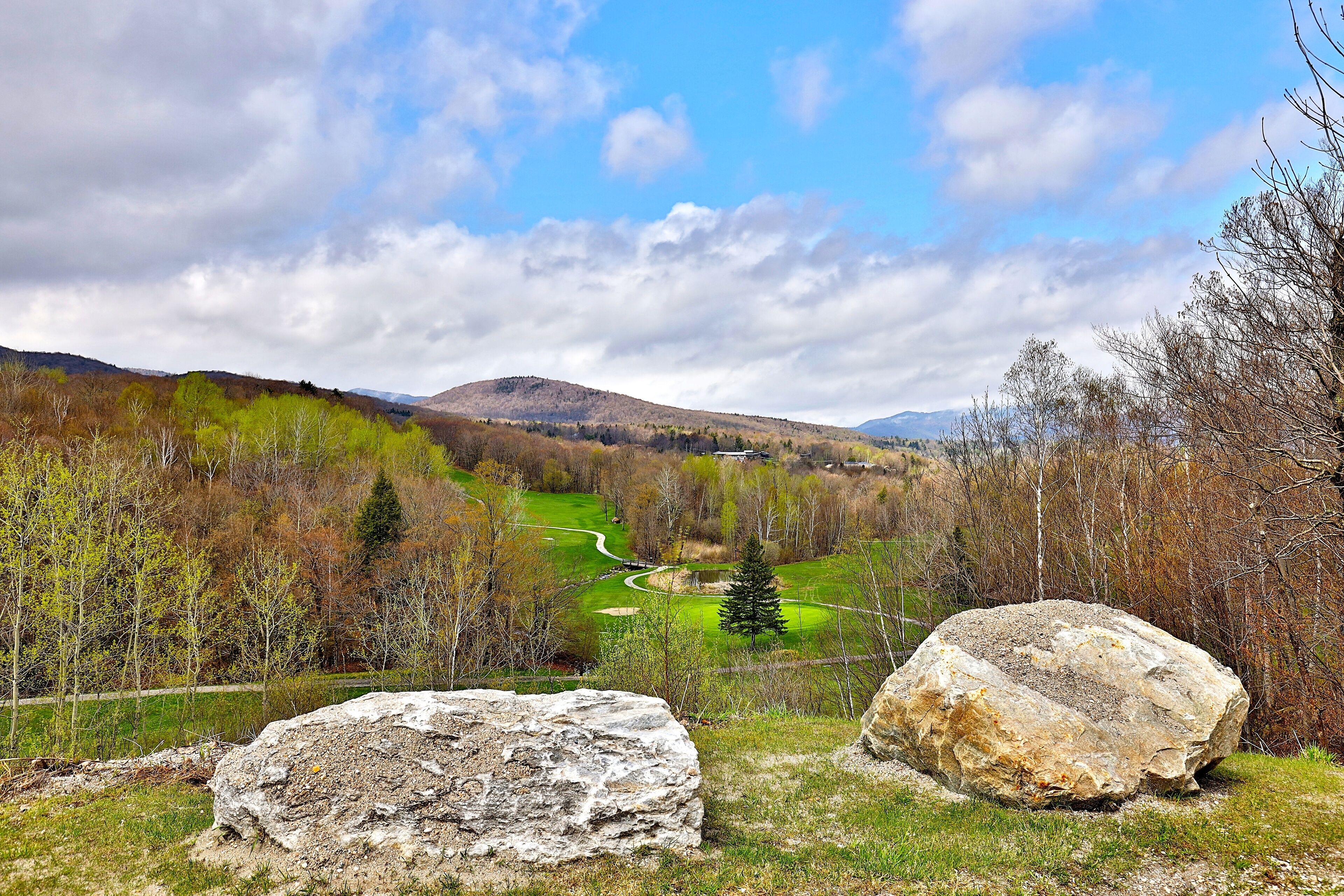 A landscape with a golf course, large rocks, and a mountainous background.
