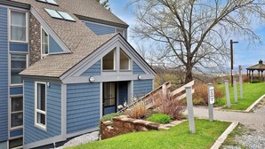 Ein blaues Haus mit schrägem Dach, einer Veranda und einer Treppe, die zum Eingang führt.