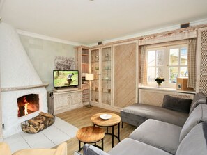 A cozy living room with a fireplace, a television, a sofa, and a small table. - Strandhuus Modern Retreat (Juist)