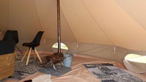 L'intérieur d'une tente, avec un réchaud portable, une chaise, une table et un tapis.