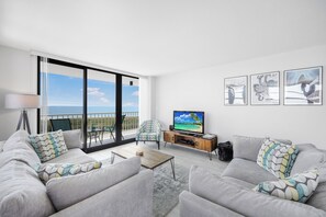 A modern living room with a sofa set, a coffee table, a TV, and artwork on the wall.