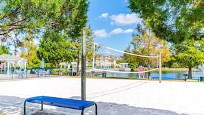 A park with a volleyball net, a blue bench, and a pond. - Villas at Seven Dwarfs 4BR, 3B, WiFi, 15min DW (Kissimmee)