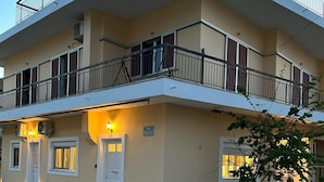 A two-story building with balconies, a ground floor entrance, and exterior lighting. - Olive Gem 2-bed Apt Sleeps 4 With Fireplace (Trifylia)