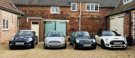 Three cars parked in front of a brick building with a garage.