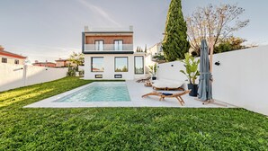 A modern house with a swimming pool, white walls, and a well-maintained lawn. - Villa Moderna con Encanto a 15 Minutos de Sevilla (Gelves)