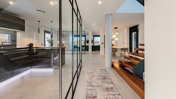 A modern kitchen with a central island, a dining area with a wooden bench, and a view of the outdoors. - Villa Moderna con Encanto a 15 Minutos de Sevilla (Gelves)