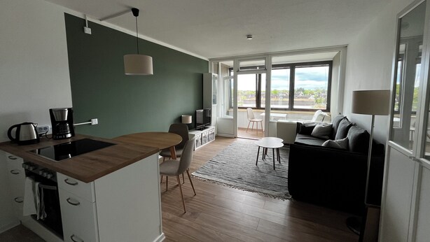 A modern kitchen with a dining area, a sofa, and a TV. - Charming apartment by the sea! (Wendtorf)