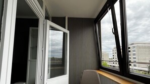 A modern room with a sliding door leading to a closet, a large window with curtains, and a white desk. - Charming apartment by the sea! (Wendtorf)