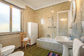Bathroom features a classic design with a bathtub, sink, and toilet, complemented by a floral tile pattern and a window.