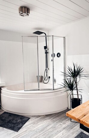 A modern bathroom with a glass-enclosed shower, a white bathtub, and a wooden table. - Panoramic View of Lake Harz (Clausthal-Zellerfeld)