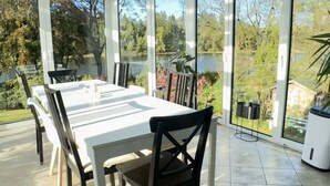 A dining area with a large table and chairs, large windows with a view of a garden and a lake. - Panoramic View of Lake Harz (Clausthal-Zellerfeld)