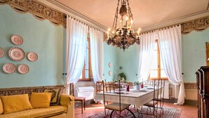 A dining area with a table set for four, surrounded by chairs, a chandelier, and a patterned rug. - Peccioli Villa Retreat (Peccioli)