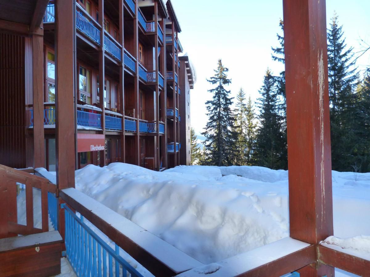 Un edificio de madera con balcones y suelo cubierto de nieve.