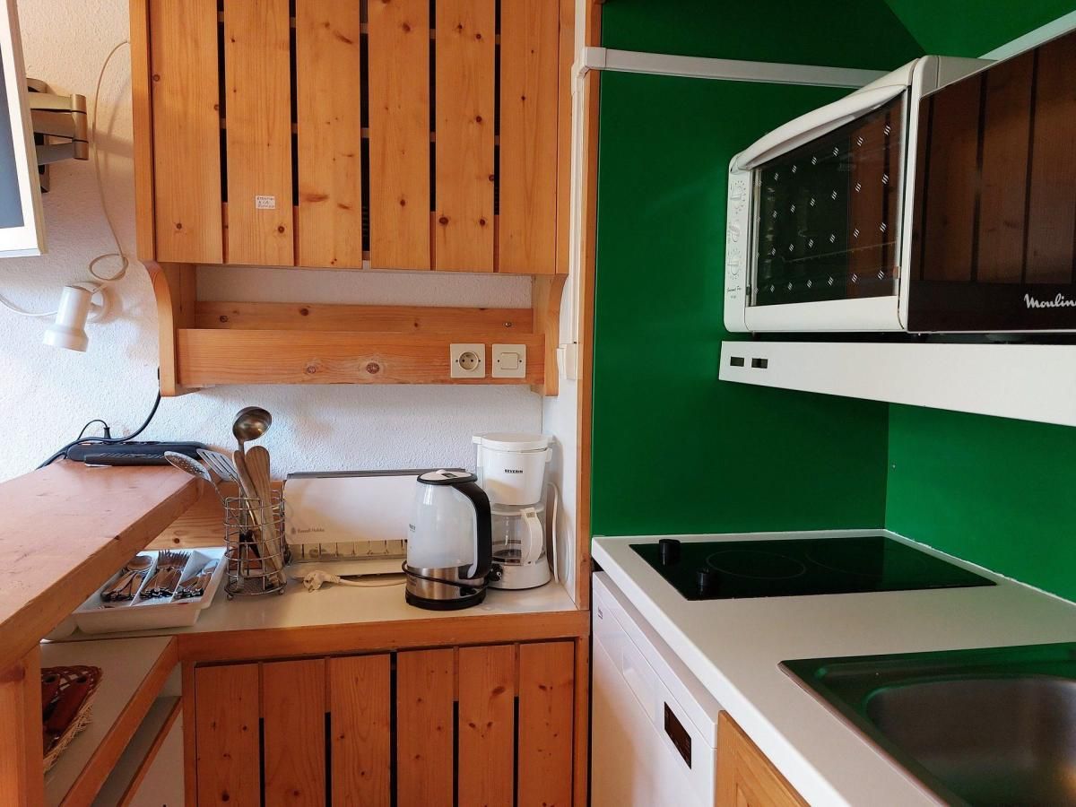 A compact kitchen with wooden cabinets, a microwave, a coffee maker, and a sink.