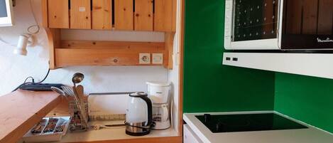 A compact kitchen with wooden cabinets, a microwave, a coffee maker, and a sink.
