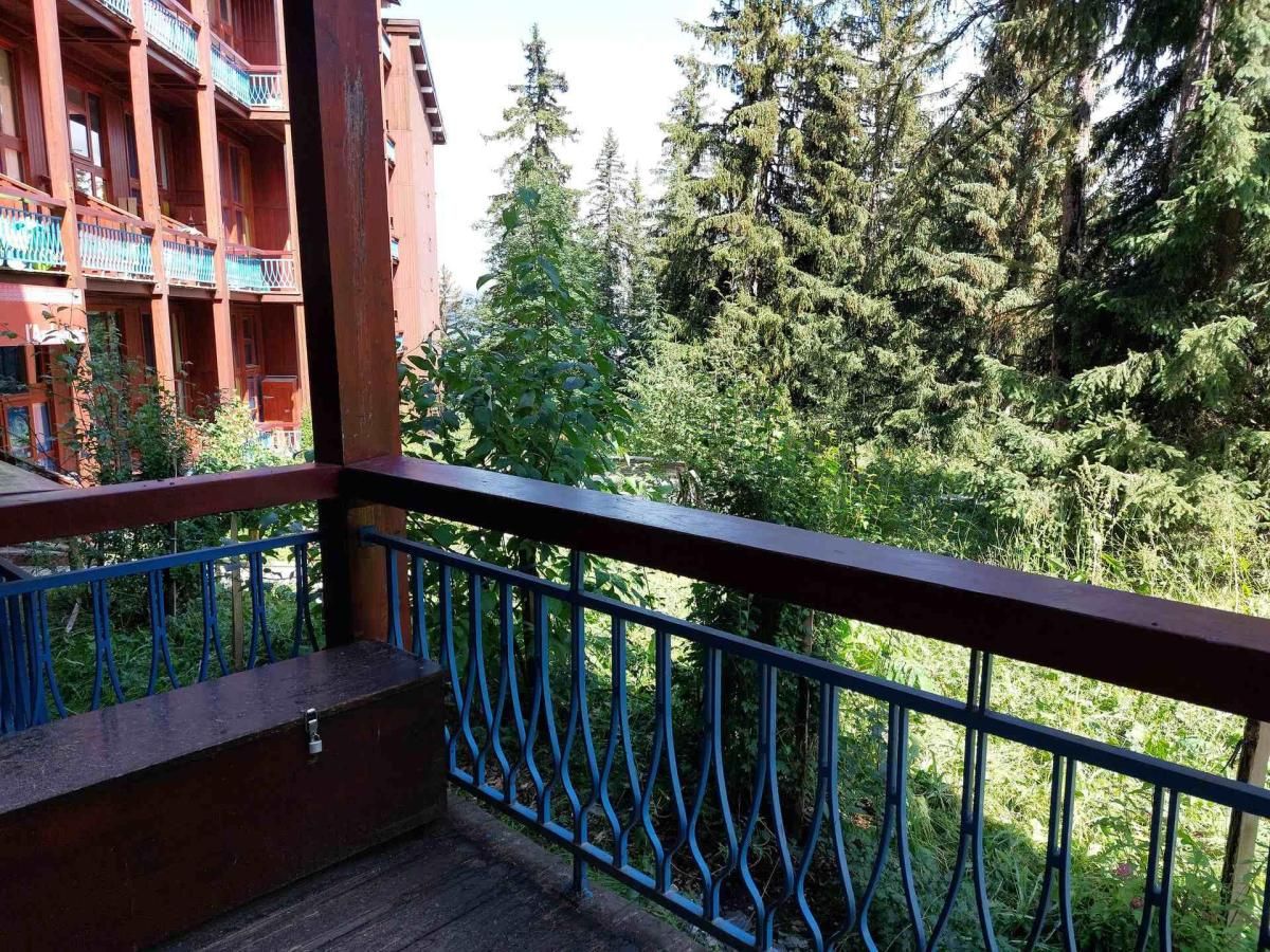 A balcony with a view of dense forest and a building with balconies.