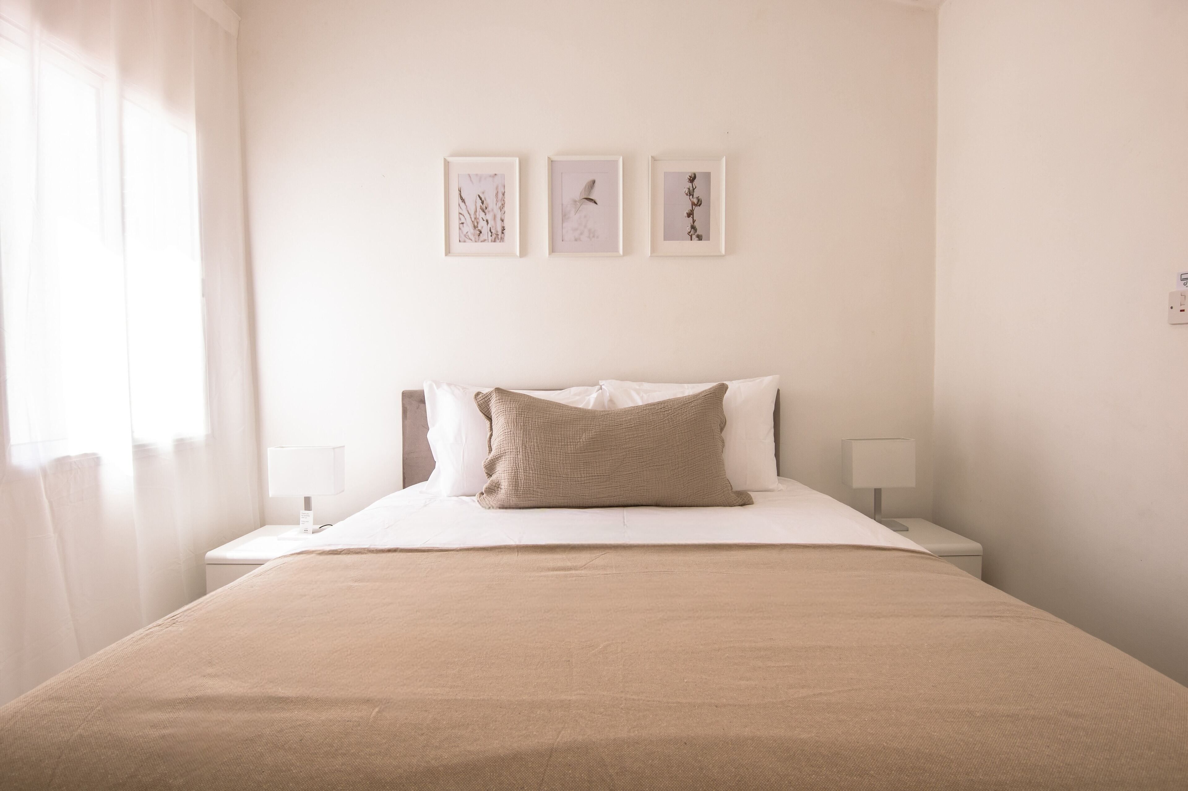 Una camera d'albergo con un letto, due comodini e tre quadri appesi al muro.
