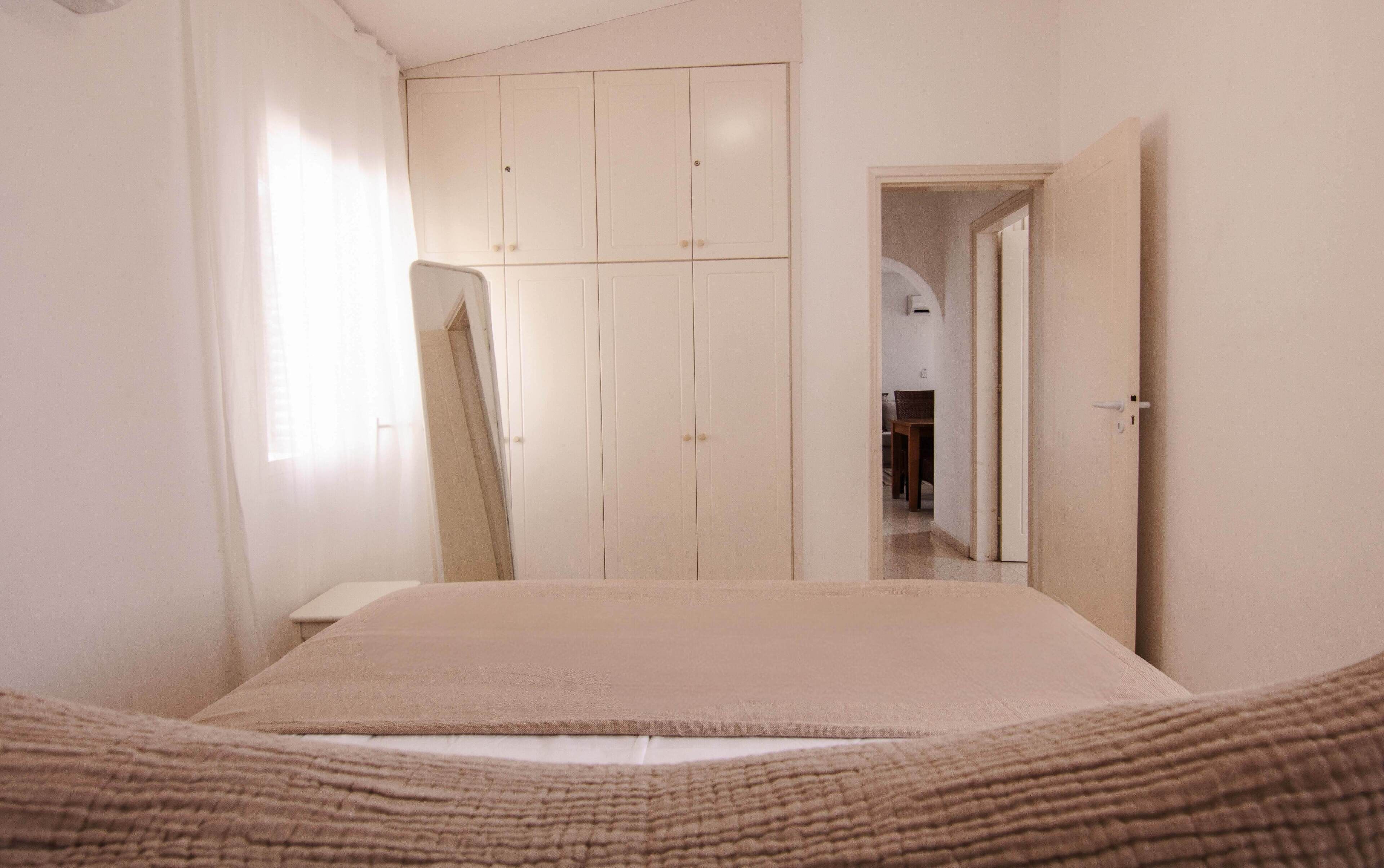 Ein Schlafzimmer mit einem Bett, einem Kleiderschrank und einer Tür zu einem anderen Raum.