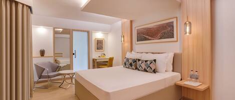 A modern hotel room with a large bed, a desk, and a chair.