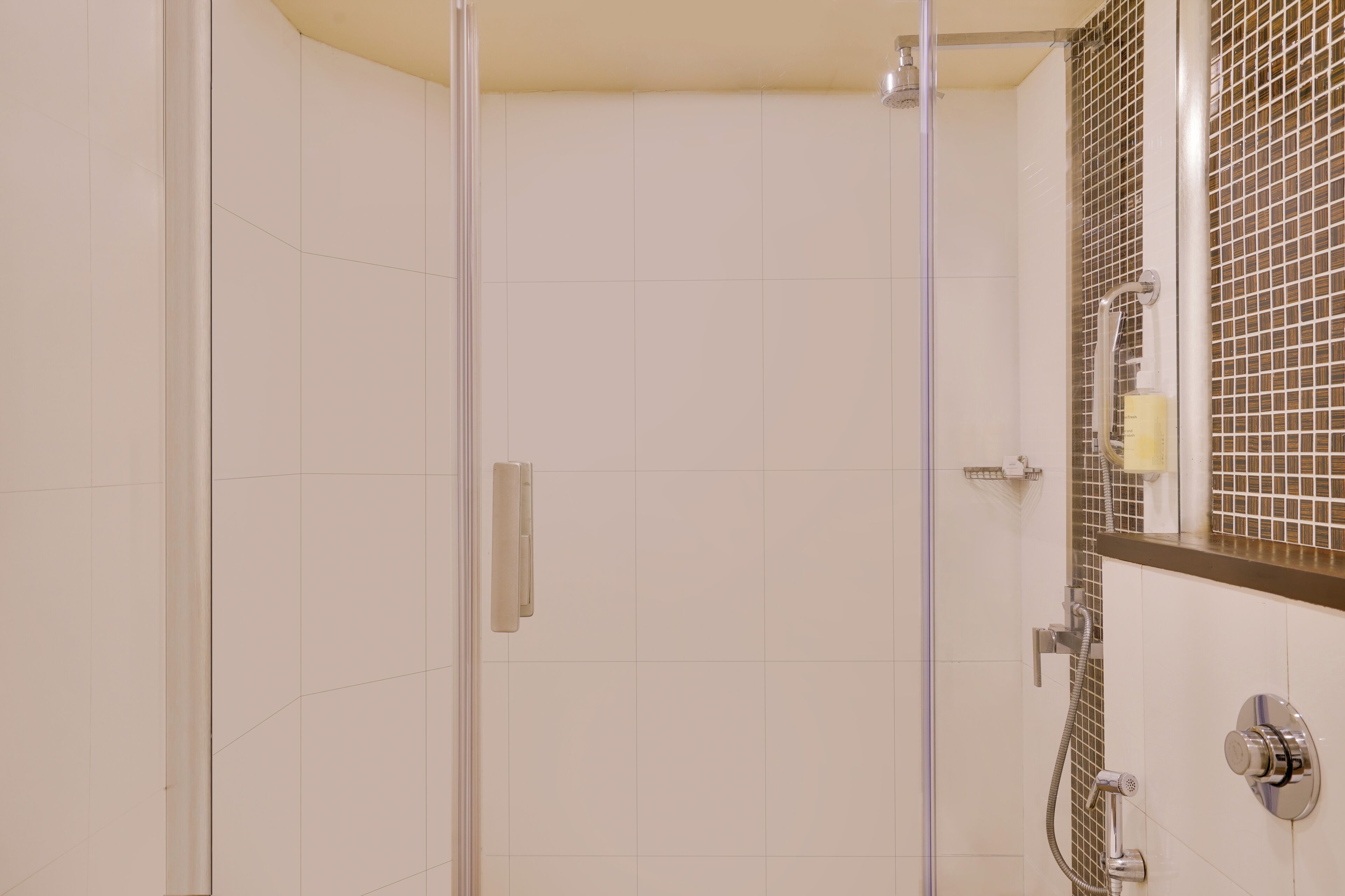 Un baño moderno con cabina de ducha de vidrio, pared azulejada y espejo con diseño de cuadrícula.