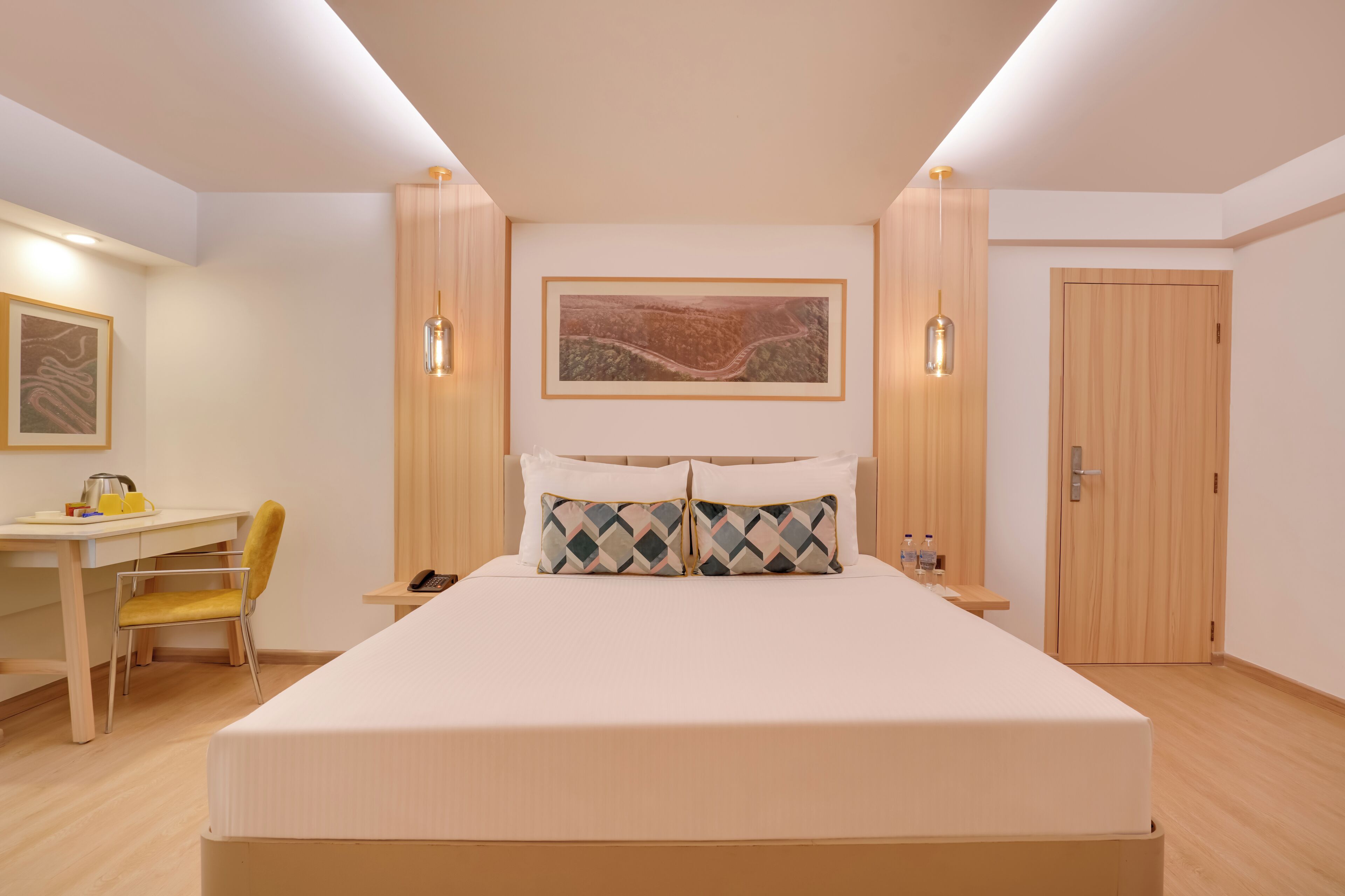 A neatly arranged bedroom with a bed, bedside table, lamp, and a desk with chair.