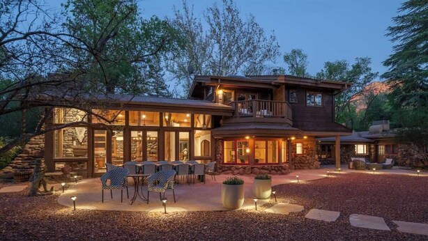 A two-story house with a stone exterior, a balcony, and a patio area with outdoor seating. - Historic Doodlebug Ranch - A Sedona Landmark (Sedona)