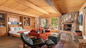 A cozy cabin interior with a stone fireplace, wooden ceiling, and a bed with a view. - Historic Doodlebug Ranch - A Sedona Landmark (Sedona)