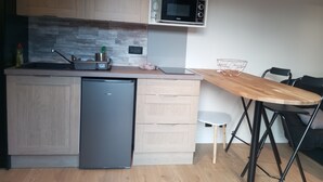 Een kleine keuken met een inbouwvaatwasser, een magnetron en een houten aanrecht.